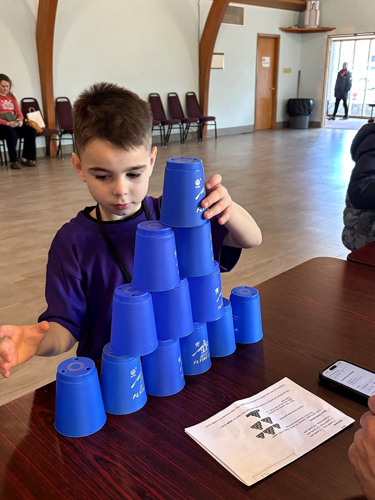 A young student carefully stacking a pyramid of cups