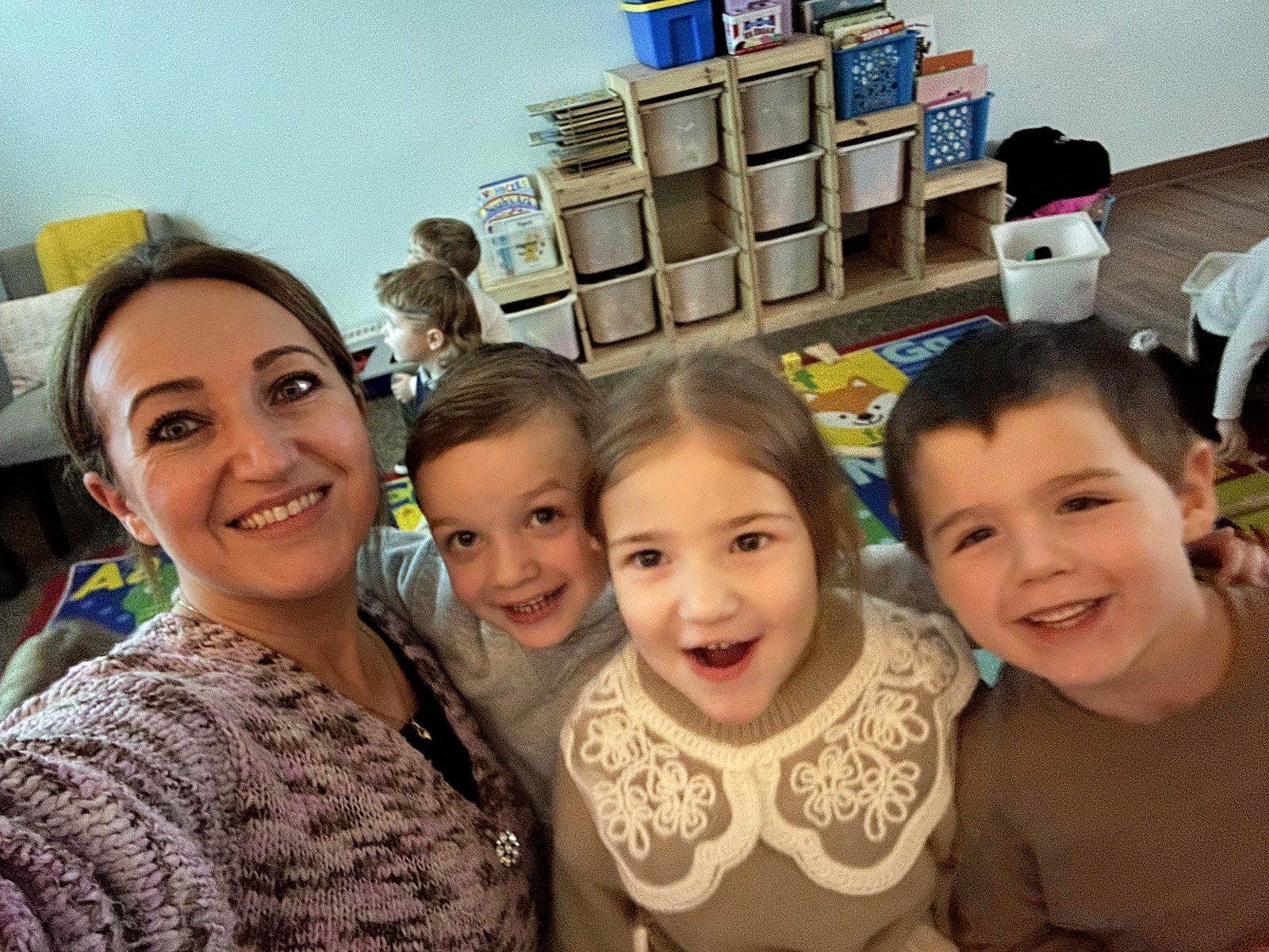 A teacher and three students smiling together in a selfie