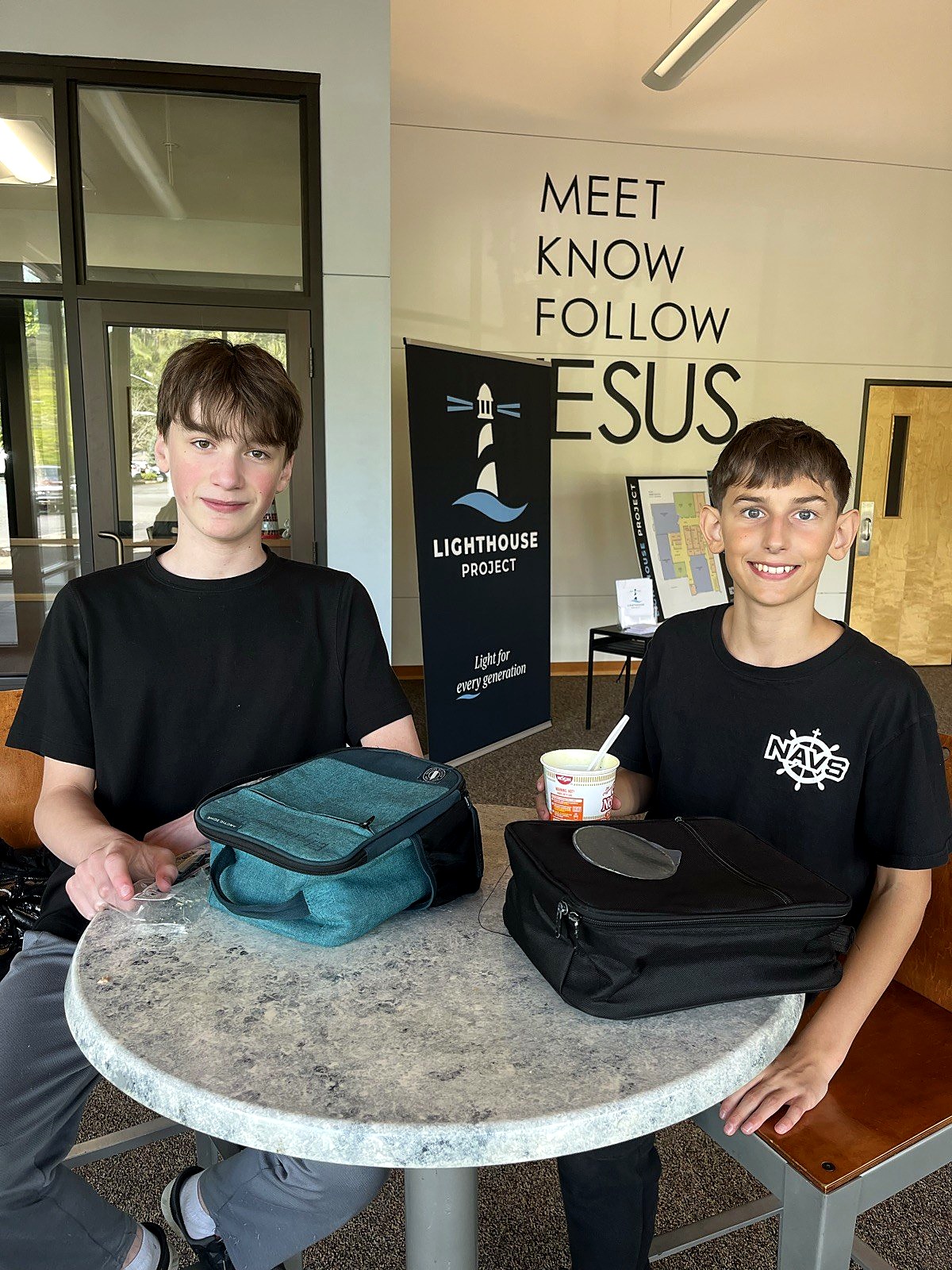 Students beside a wall that reads Meet, Know, Follow Jesus
