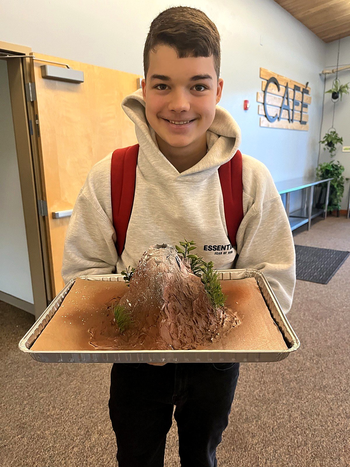 A student proudly holding the volcano model he built