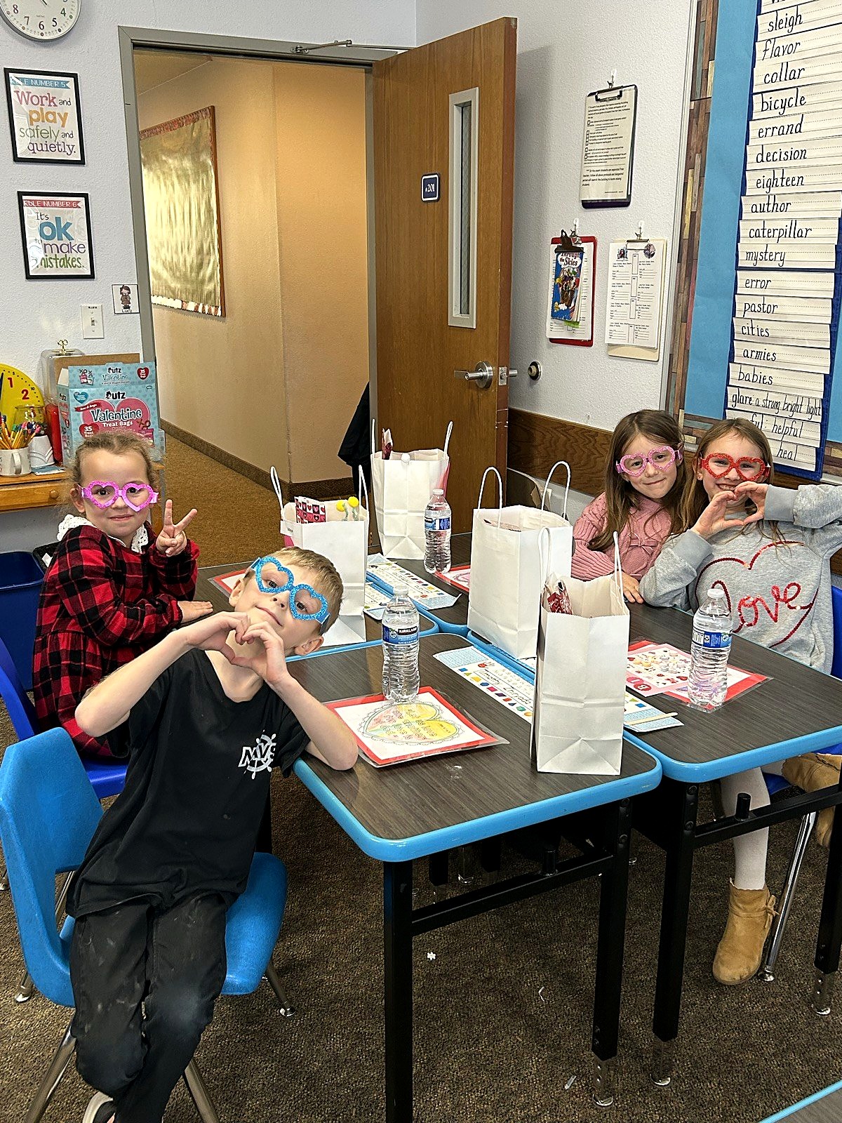 Elementary students wearing fun glasses and making heart hands on spirit day